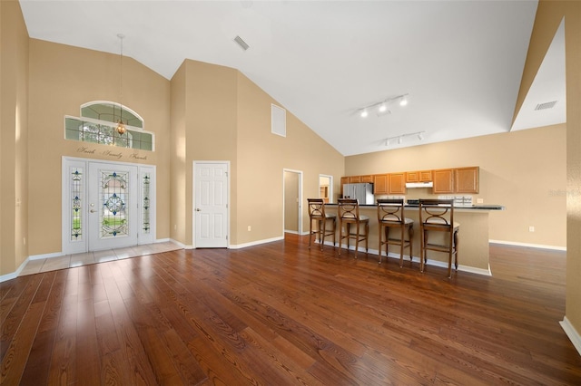 entrance foyer with dark wood-style floors, visible vents, high vaulted ceiling, and baseboards