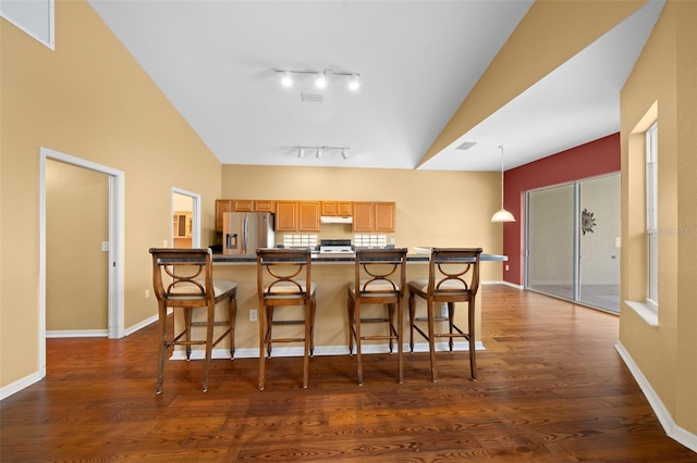 kitchen with vaulted ceiling, stove, stainless steel refrigerator with ice dispenser, and dark wood-style flooring