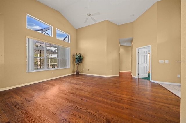 unfurnished room with baseboards, high vaulted ceiling, and wood finished floors