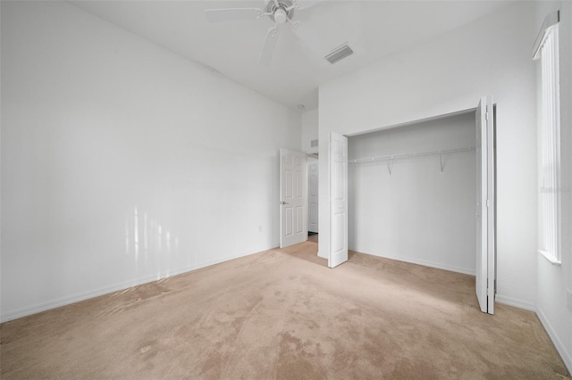 unfurnished bedroom featuring carpet flooring, visible vents, baseboards, a ceiling fan, and a closet