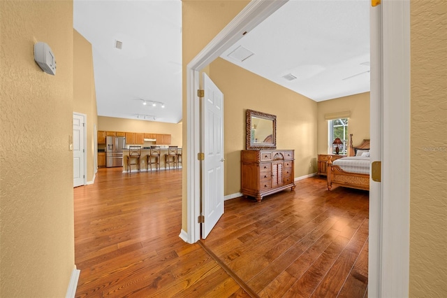 hall with visible vents, track lighting, hardwood / wood-style flooring, and baseboards