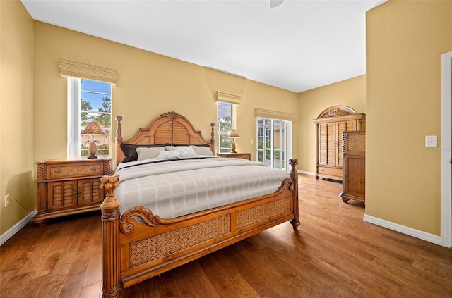 bedroom featuring access to exterior, baseboards, and wood finished floors