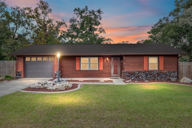 single story home featuring a garage and a lawn