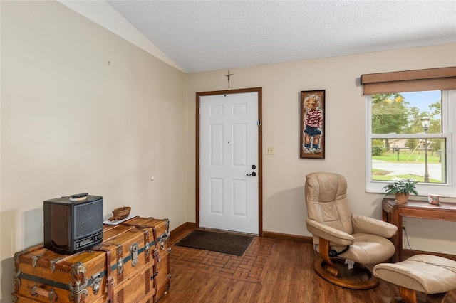 entryway featuring dark wood-type flooring, a textured ceiling, and lofted ceiling