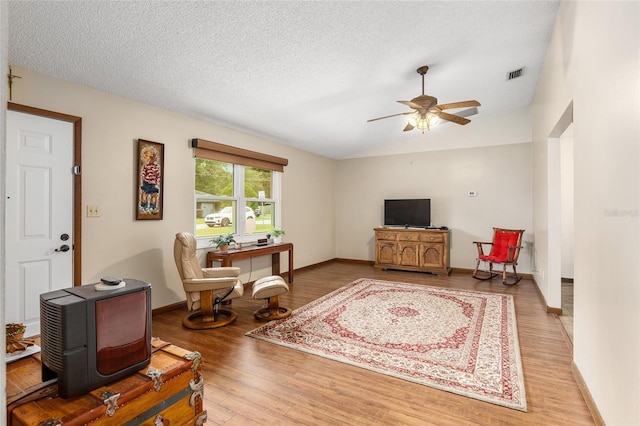 living room with a textured ceiling, light wood-type flooring, and ceiling fan