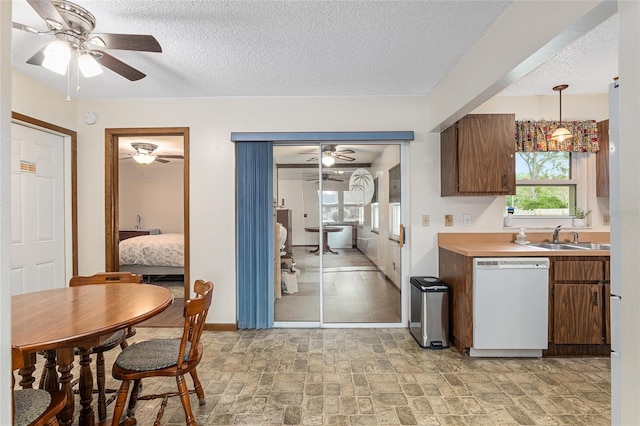 kitchen featuring white dishwasher, a textured ceiling, sink, and decorative light fixtures