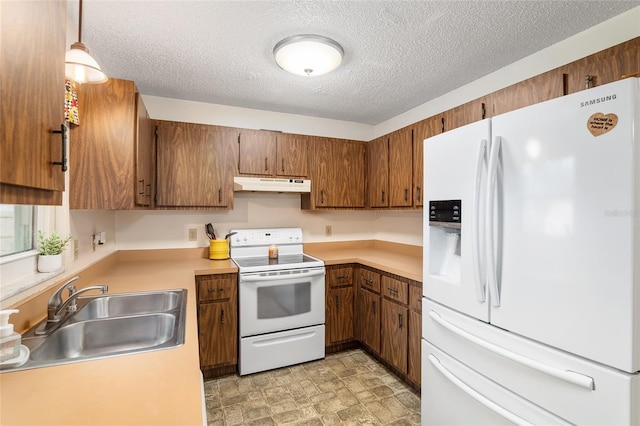 kitchen featuring decorative light fixtures, white appliances, sink, and a textured ceiling