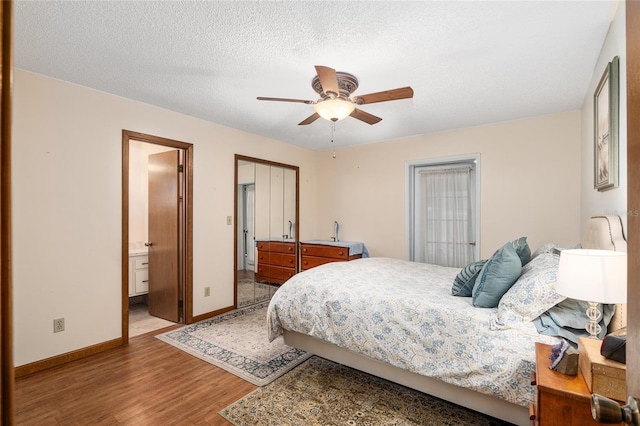 bedroom featuring ensuite bathroom, ceiling fan, a textured ceiling, and wood-type flooring