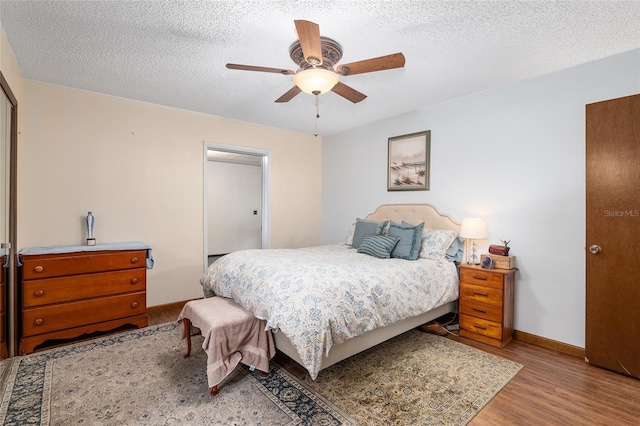 bedroom with ceiling fan, a textured ceiling, and light hardwood / wood-style flooring