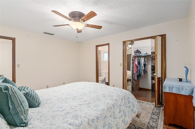 bedroom with ensuite bath, ceiling fan, a textured ceiling, hardwood / wood-style floors, and a closet