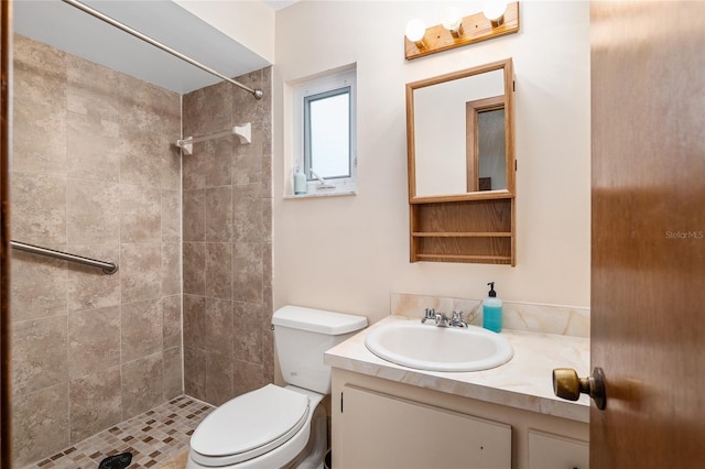 bathroom featuring toilet, vanity, and tiled shower