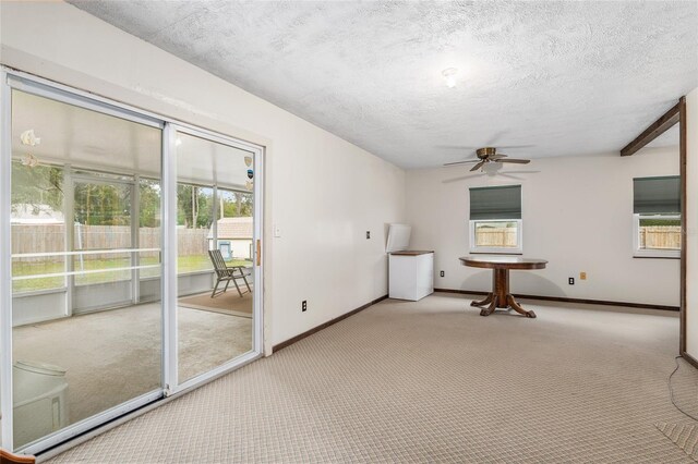 carpeted empty room featuring a textured ceiling, a healthy amount of sunlight, and ceiling fan