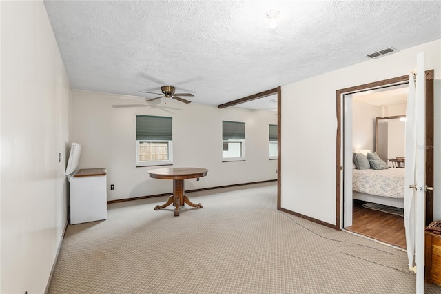 interior space featuring a textured ceiling, light carpet, and ceiling fan