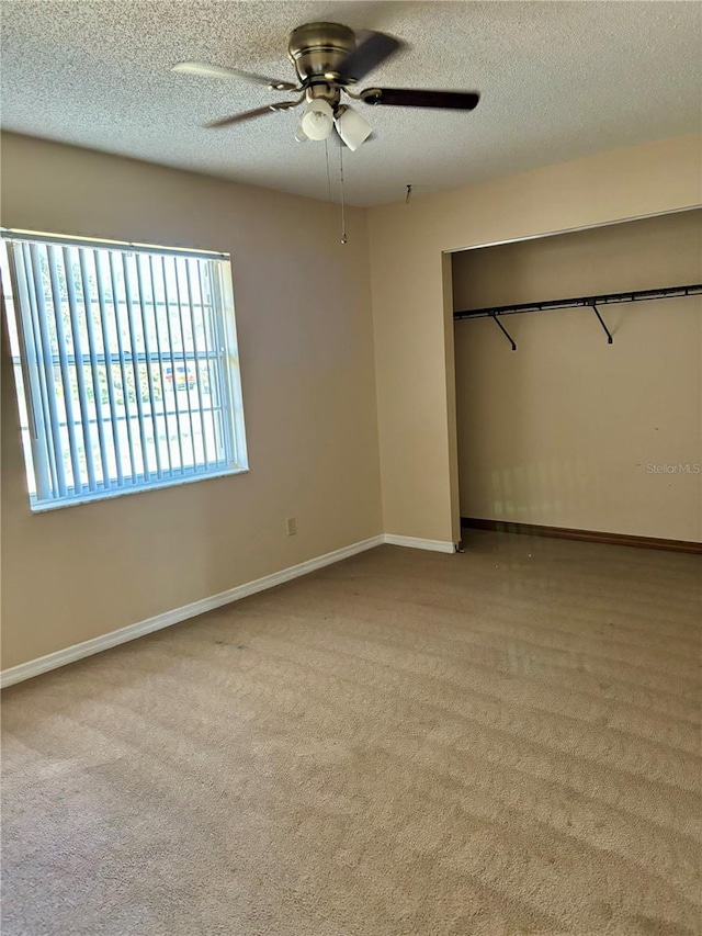 unfurnished bedroom with ceiling fan, light colored carpet, a textured ceiling, and a closet