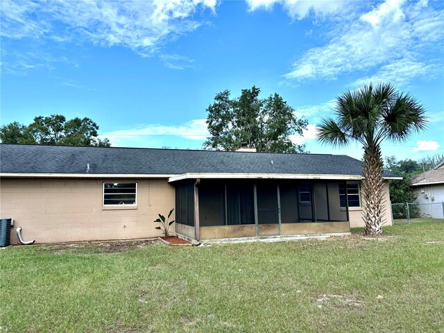 rear view of house featuring a sunroom, central AC, and a lawn