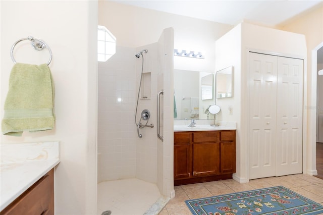 bathroom with tile patterned flooring, tiled shower, and vanity