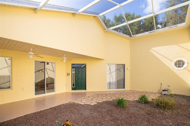 back of property featuring glass enclosure, ceiling fan, and a patio area