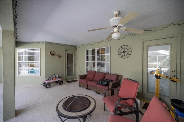 carpeted living room with a textured ceiling and ceiling fan