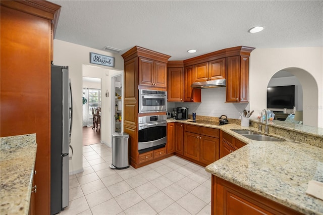 kitchen with light stone countertops, appliances with stainless steel finishes, sink, and light tile patterned floors