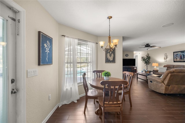 dining space featuring dark wood-type flooring, ceiling fan with notable chandelier, and a textured ceiling