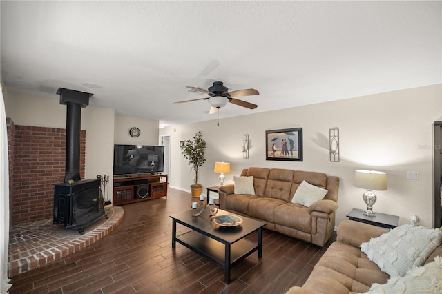 living room featuring dark hardwood / wood-style flooring, a wood stove, and ceiling fan