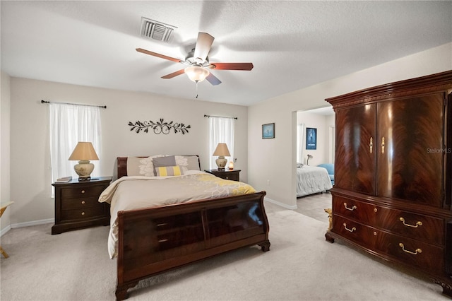 bedroom featuring a textured ceiling, light carpet, and ceiling fan