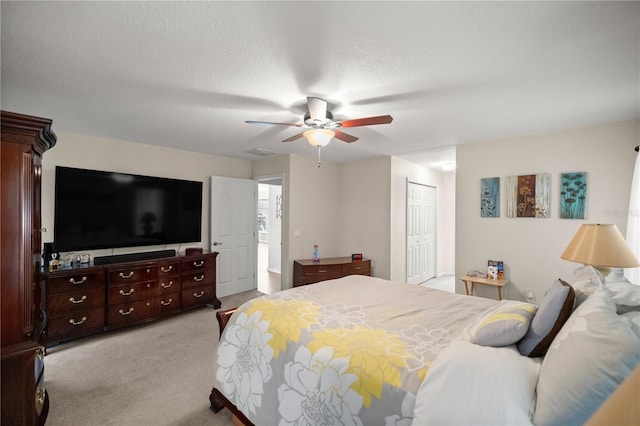 bedroom featuring a closet, a textured ceiling, light colored carpet, and ceiling fan