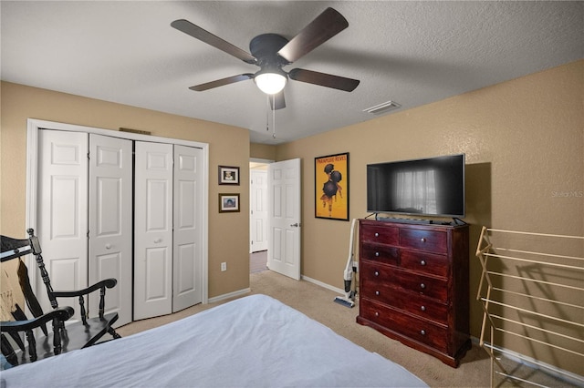 carpeted bedroom with a textured ceiling, ceiling fan, and a closet