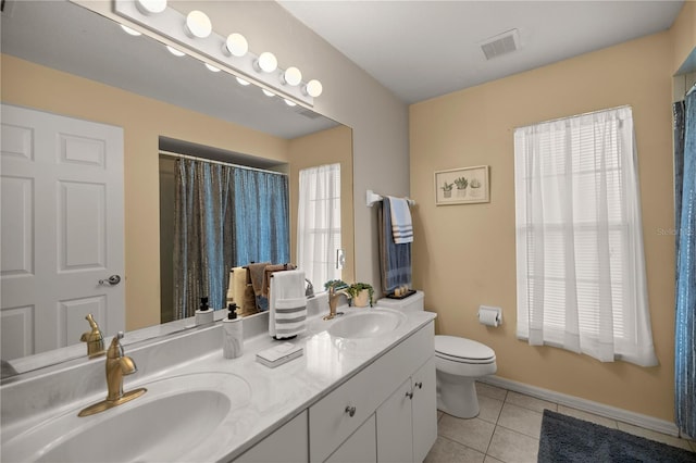 bathroom with toilet, a wealth of natural light, vanity, and tile patterned floors