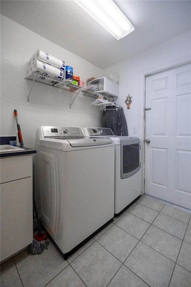 washroom with washing machine and dryer, a textured ceiling, and light tile patterned flooring