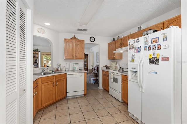 kitchen with light tile patterned floors, white appliances, a textured ceiling, and sink