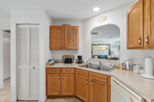 kitchen with sink, white dishwasher, light tile patterned flooring, and a textured ceiling