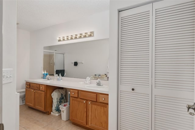 bathroom with tile patterned floors, vanity, toilet, and a textured ceiling