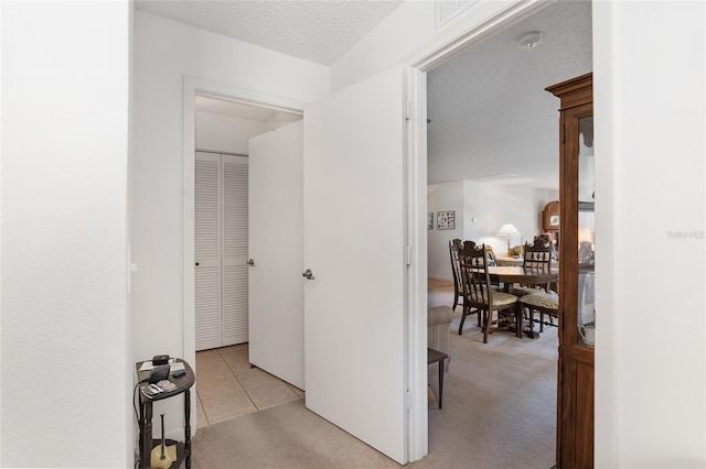 corridor featuring light carpet and a textured ceiling