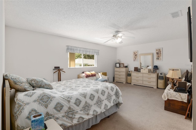 bedroom with ceiling fan, light colored carpet, and a textured ceiling