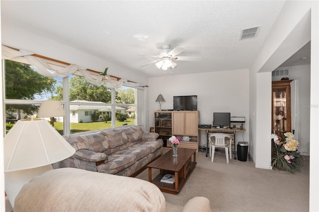 carpeted living room featuring ceiling fan and a textured ceiling