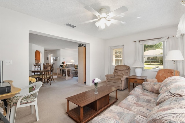 carpeted living room featuring ceiling fan and a textured ceiling