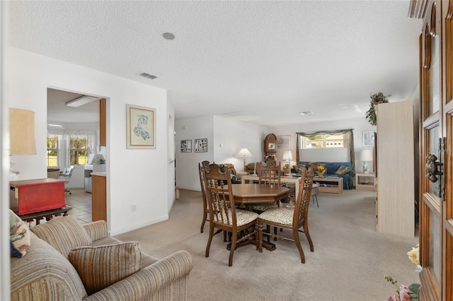 dining room with a textured ceiling and light carpet