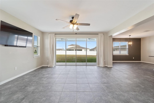 empty room with ceiling fan with notable chandelier and tile patterned floors