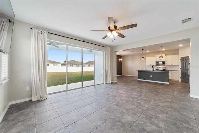 unfurnished living room featuring sink, tile patterned floors, and ceiling fan