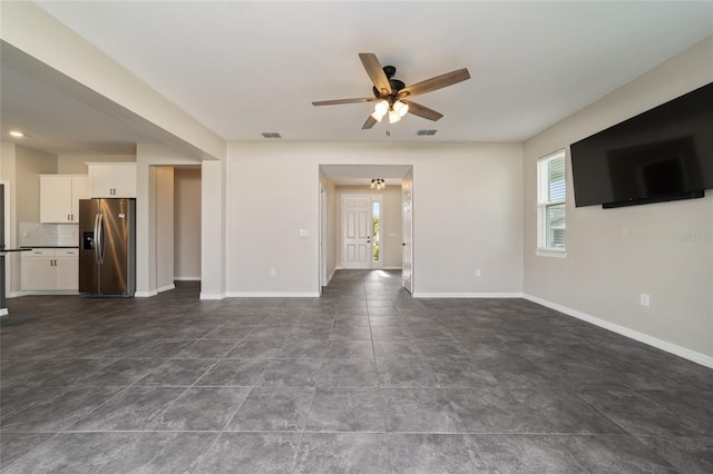 unfurnished living room with dark tile patterned flooring and ceiling fan