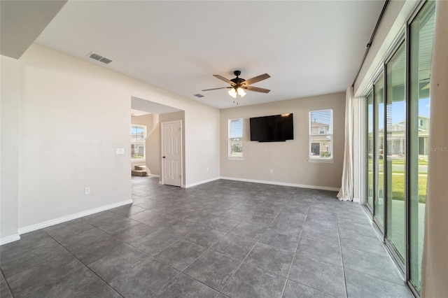 empty room featuring ceiling fan and dark tile patterned floors