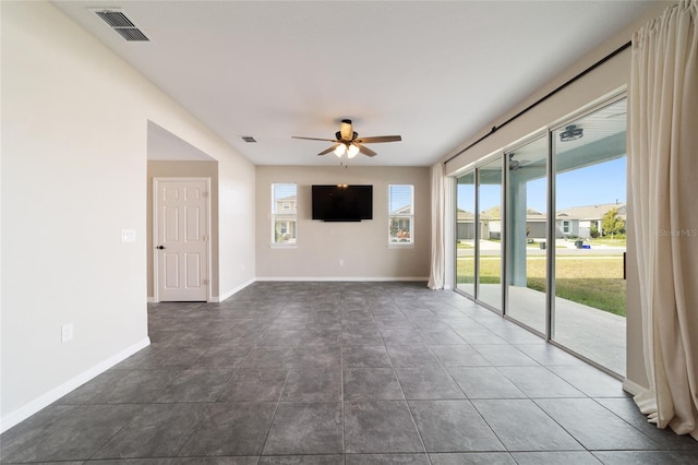 unfurnished living room featuring dark tile patterned floors and ceiling fan