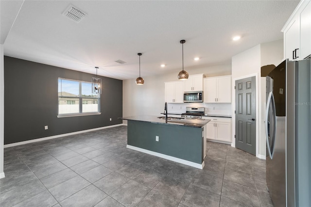 kitchen featuring stainless steel appliances, white cabinets, sink, an island with sink, and decorative light fixtures