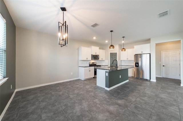 kitchen featuring a center island with sink, sink, appliances with stainless steel finishes, decorative light fixtures, and white cabinets