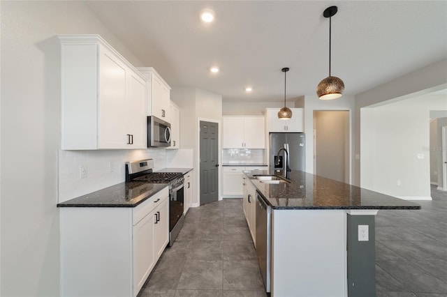 kitchen with stainless steel appliances, white cabinets, sink, and an island with sink