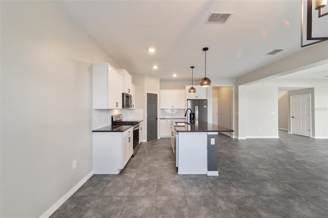 kitchen with stainless steel appliances, a center island with sink, white cabinets, sink, and decorative light fixtures