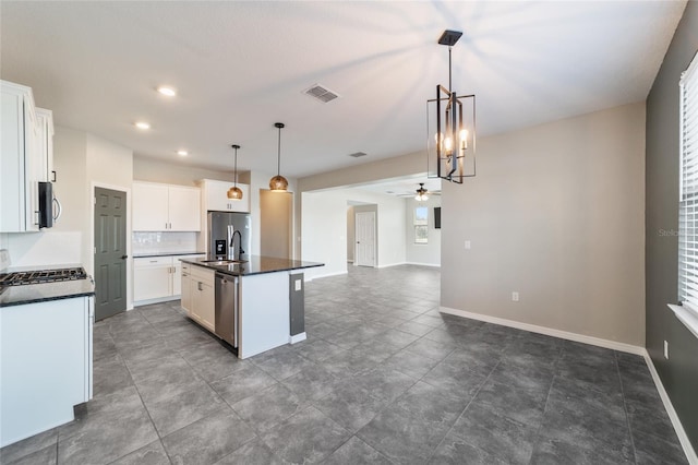 kitchen with stainless steel appliances, a center island with sink, ceiling fan, decorative light fixtures, and white cabinets