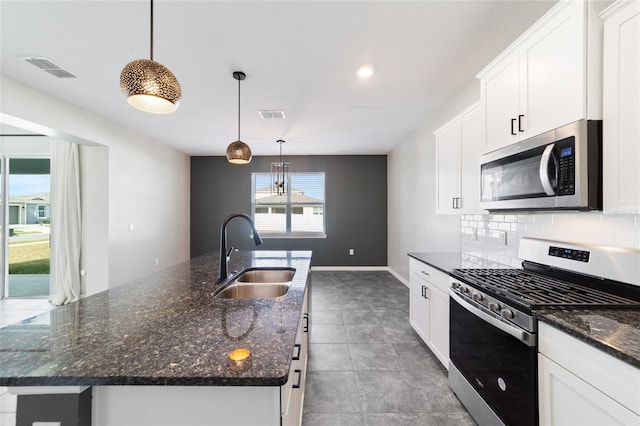 kitchen with an island with sink, sink, pendant lighting, and appliances with stainless steel finishes