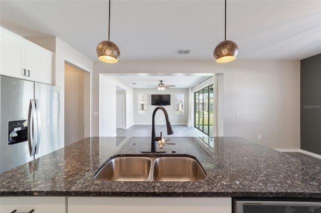 kitchen featuring stainless steel appliances, dark stone counters, white cabinets, sink, and decorative light fixtures